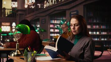 maturo donna lettura e scrittura a un' Università città universitaria biblioteca, Lavorando su tesi con intellettuale ambizione e dedizione per vita lungo apprendimento e personale risultato. telecamera un. video