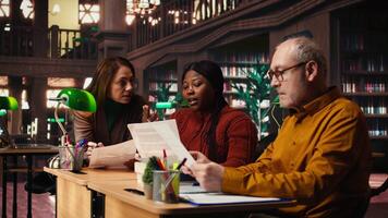 volwassen team van artiesten repeteren script dialoog samen in een bibliotheek, maken drama Speel rol voorbereidende werkzaamheden voor karakter ontwikkeling. inzet naar acteren en dramaturgie. camera a. video