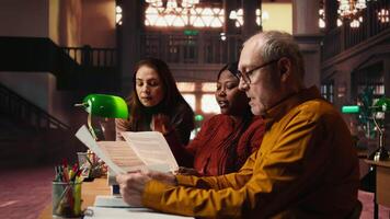 verschillend acteurs team lezing hun scripts gedurende theater drama Speel repetitie in bibliotheek, tonen toewijding naar script oefening. rol voorbereiding samen voor dramatisch kunsten heropvoering. camera a. video