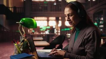 más viejo mujer escuchando a en línea documental en el tema ella estudios, tomando notas y hallazgo más pertinente información. completando su clase notas en orden a pasar el exámenes cámara una. video