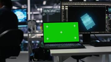 Close up of mockup laptop in server room where worker uses AI to review diagnostics. Admin in data center analyzing performance data using artificial intelligence on isolated screen notebook, camera A video