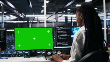 Data center manager overseeing team of technicians managing AI systems using green screen PC. Supervisor checking work of teamworking server hub colleagues using mockup computer, camera A video