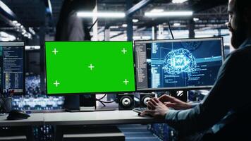 Data center engineer managing AI systems for uptime and efficiency using mockup PC. IT professional using artificial intelligence on isolated screen computer in server hub, camera A video