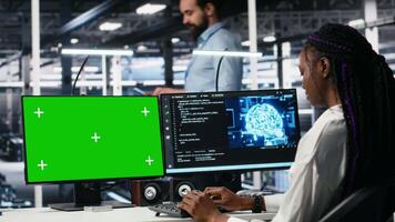 Data center engineers managing AI systems for uptime and efficiency using chroma key PC. Teamworking IT specialists using artificial intelligence on green screen computer in server hub, camera A video
