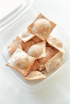 A Delicious Assortment of Freshly Made Ravioli Placed Neatly in a Container, Dusting of Flour Accentuating Their Soft Texture and Shape photo