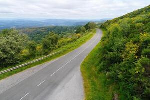 Road trip concept a curved road in the green hills of Galicia, Spain. photo