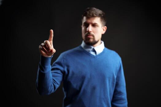 Engaging man gestures with one finger to convey a message in a dark studio setting photo