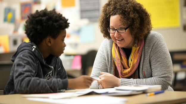 Teacher providing one on one support to student in classroom setting photo