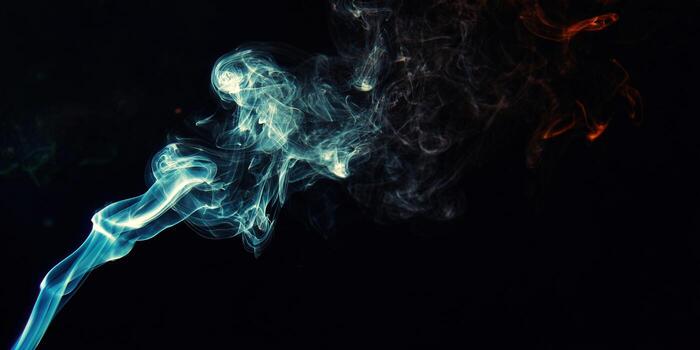 Vibrant teal and orange smoke elegantly swirls on a dark background, creating an artistic and dynamic composition. photo