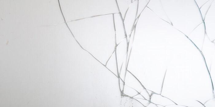 Intricate patterns of fractures adorn a cracked glass surface, against a white backdrop. photo