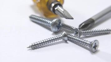 en makro skott av skruvar och skruvmejsel tips om på en vit yta, betona de begrepp av verktyg, hårdvara, och hantverk i de rike av konstruktion video