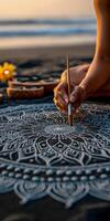 Artist paints mandala on black sand beach at sunset in Bali photo