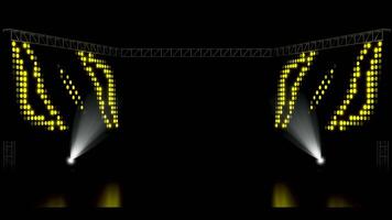A dark concert or event stage with two spotlights illuminating the floor. Large LED screens display abstract colorful dot patterns under a metal truss structure, creating a dynamic visual background. video