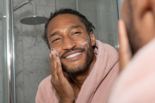 A man in a pink robe is smiling while looking in the mirror photo