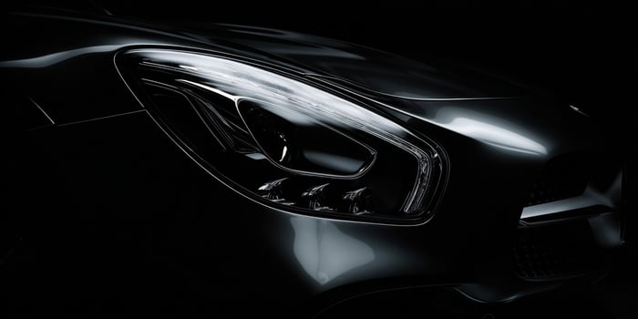 The sleek car headlight illuminated in a dramatic dark setting. photo