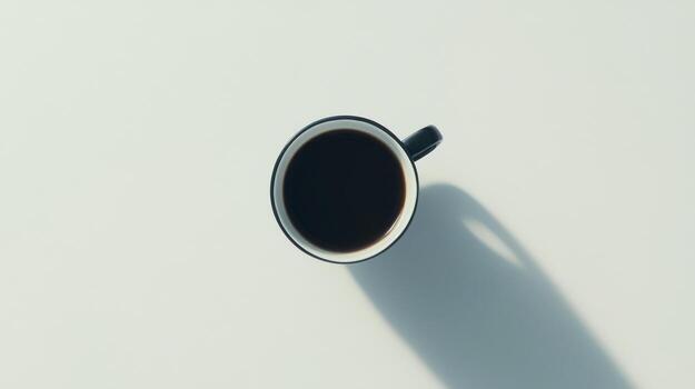 High-angle view of a dark coffee mug on a light surface. Soft shadows cast photo