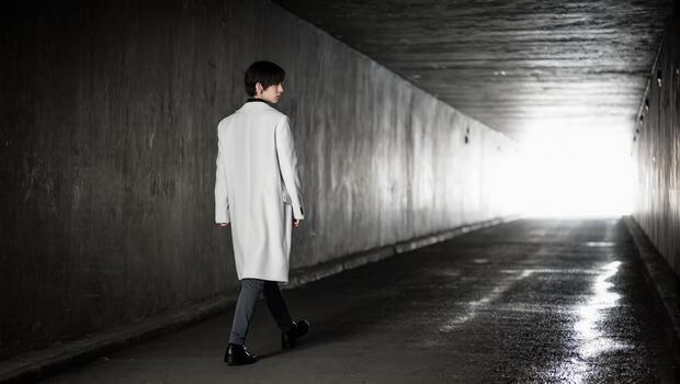 A lone figure walks through a dark tunnel towards a bright, hopeful light, embodying a journey of determination and the pursuit of new beginnings. photo