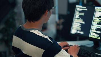 Back view programmer typing code dual screen monitor application development debugging system process task video