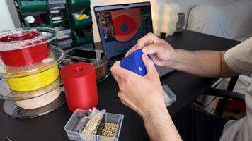 en person Arbetar på en 3d utskrift projekt, omgiven förbi färgrik tråd spolar och en bärbar dator visning en design, highlighting innovation och kreativitet video