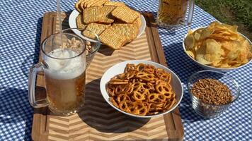 A picnic setup with pretzels, crackers, and beer on a checkered tablecloth evokes summer, relaxation, and leisure The scene includes snacks and beverages video