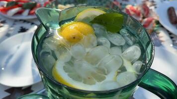Refreshing lemonade in a green pitcher, perfect for summer gatherings and picnics, with lemon slices and mint leaves adding zest video