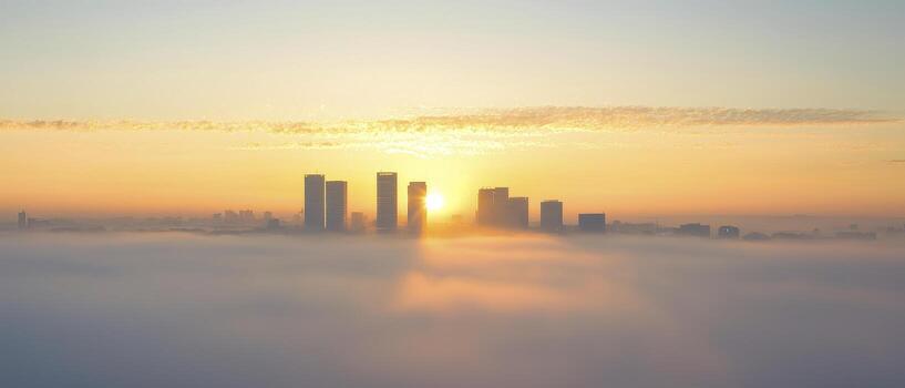 City skyline at dawn covered in dense fog with golden sunlight creating peaceful and serene atmosphere photo