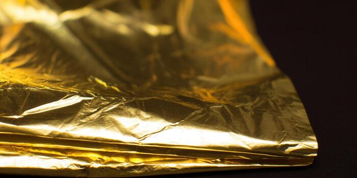 Intriguing close-up of gold foil, capturing its shimmering texture and exquisite detail on a dark surface. photo