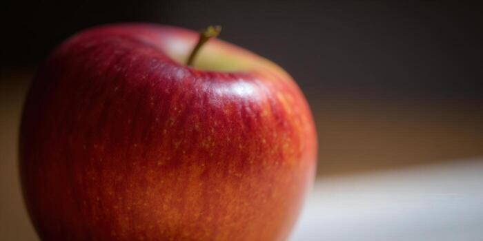 A close-up shot of a vibrant red apple with a smooth, glossy skin. photo