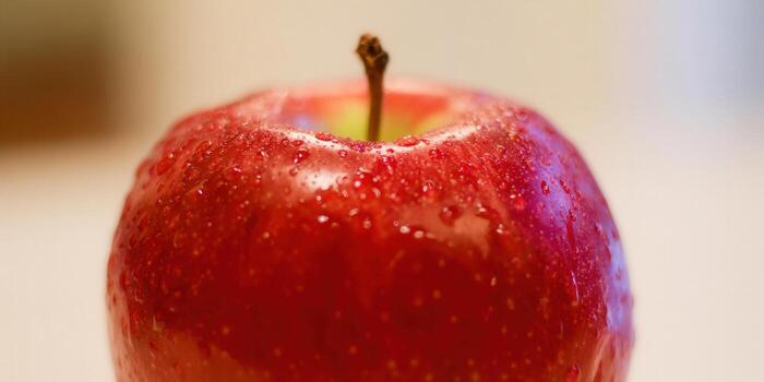 A close-up of a shiny, red apple, showcasing its freshness with water droplets. photo