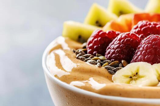 Smoothie bowl topped with fresh raspberry, banana slice, kiwi, and seeds for healthy breakfast treat photo