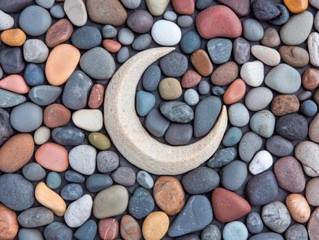 Crescent moon carved from stone surrounded by colorful pebbles photo