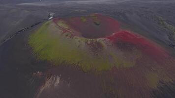 aereo Visualizza di un' vulcanico cratere nel Islanda con rosso e giallo piste, buio terreno, e strutturato minerale modelli. il telecamera si sposta senza intoppi in testa. video