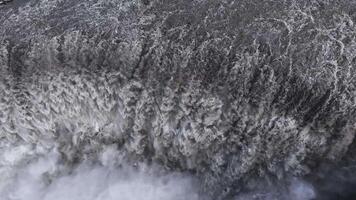 continuo turbulento agua fluye terminado dettifoss cascada en Islandia, con niebla creciente desde el base y exhibiendo sus inmenso poder y escala. video