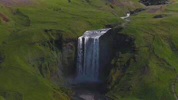 antenn se av skogafoss vattenfall i Island, cascading in i en slå samman Nedan. dimma stiger som vatten flöden, med en väg och trappa synlig närliggande. video
