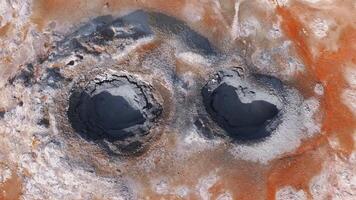 antenn se av hverir geotermisk område i Island, som visar orange och vit mineral insättningar och dynamisk bubblande lera pooler med krusningar och stänk. video