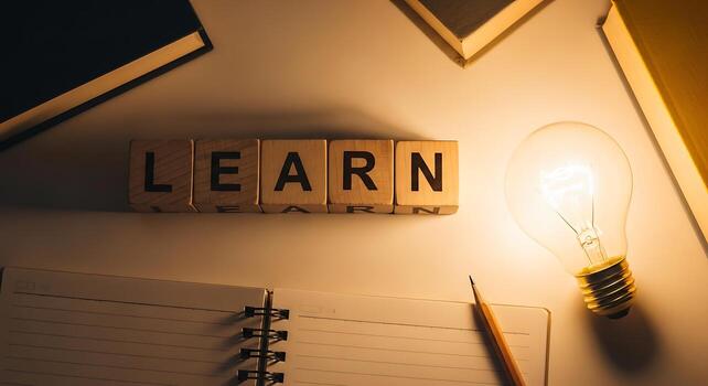 Wooden blocks spell out learn next to a glowing lightbulb photo