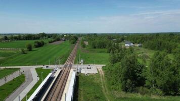 panoramico ferrovia stazione Visualizza con brani estendendosi in il orizzonte, delimitato di vivace verde i campi e alberi, la creazione di un' tranquillo e invitante atmosfera video