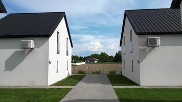 contemporaneo architettura con Due bianca edifici con nero tetti, collegato di un' sentiero, circondato di verdura e Aperto i campi sotto un' chiaro cielo video