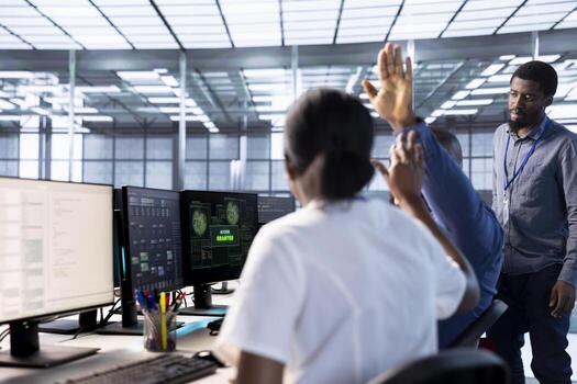 Engineer doing high five gesture with colleague after receiving access granted notification while reconfiguring server hub. Data center staff members celebrating successfully eliminating all errors photo