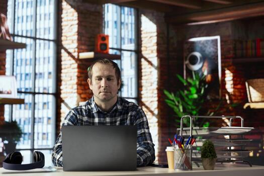 Man seated at home office desk using laptop, checking emails displayed on screen, reading messages in inbox, composing and sending replies, managing electronic correspondence, organizing email folders photo
