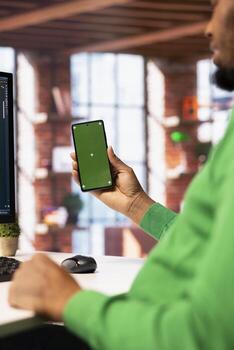 Man enjoying leisure time in apartment, using isolated screen cellphone to text friends. Person talking with mates on social network internet website using chroma key mobile phone, close up photo