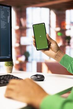 Man enjoying leisure time at home, using green screen smartphone to text friends. Person talking with mates on social network online website using mockup mobile phone, close up photo