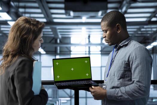 Engineer in data center using green screen laptop, refining server virtualization strategies, configuring cluster nodes, adjusting routing rules, maintaining efficient workflows photo