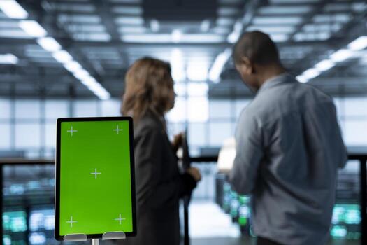 Close up of mockup tablet next to server room data scientists conducting security audits, preventing bugs. Green screen device and african american man with colleague in data center photo