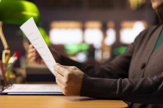 Mature woman focused on university level reading and studying, surrounded by textbooks and documents in a calm quiet study area designed for academic preparation and reflection. Coursework. photo