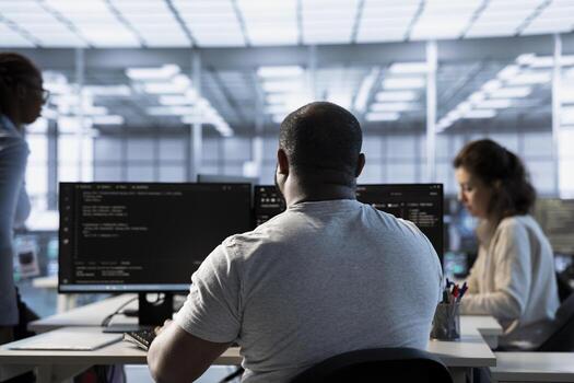 Admin in server hub next to colleagues tasked with protecting data against hacking attacks. African american worker and coworkers safeguarding data center against unauthorized access photo