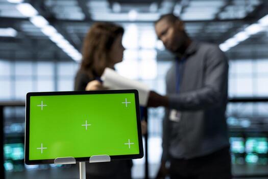Focus on isolated screen tablet in data center with engineers in blurry background employing machine learning models. Close up of mockup device used by teamworking server hub IT experts photo
