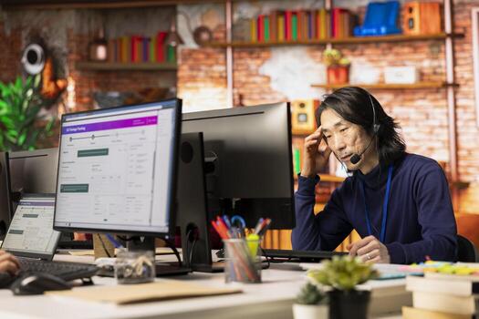 Call center agent tracking shipments at work, looking at computer screen, handling delivery delays. Asian customer center worker using software to locate clients packages and provide status updates photo