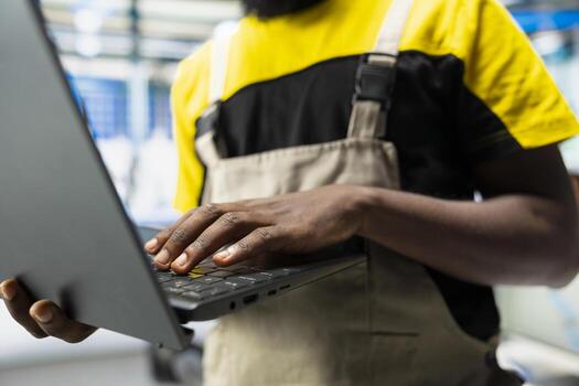 Black technician works on solar energy software settings in high tech factory, optimizing the production process. Optimal system configuration with digital tools and industrial robotics. photo