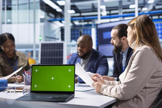 Industrial plant coworkers identifying technical bottlenecks using chroma key notebook. Teamworking businesspeople in factory office analyzing data, reviewing system health metrics with mockup laptop photo